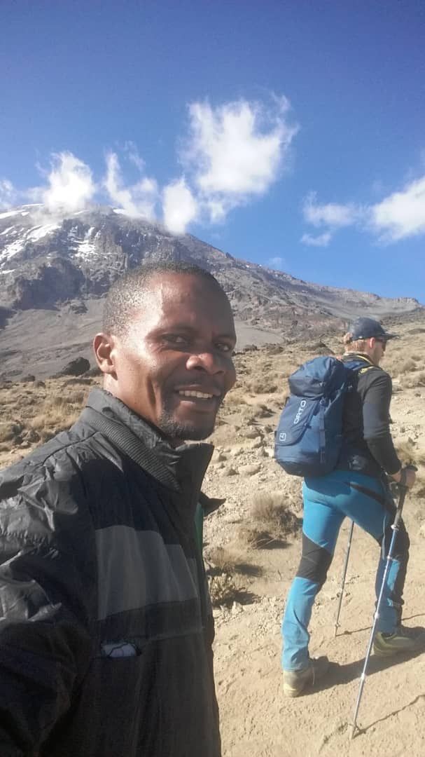 Mango, our lead guide, smiling on the trail with Kibo behind