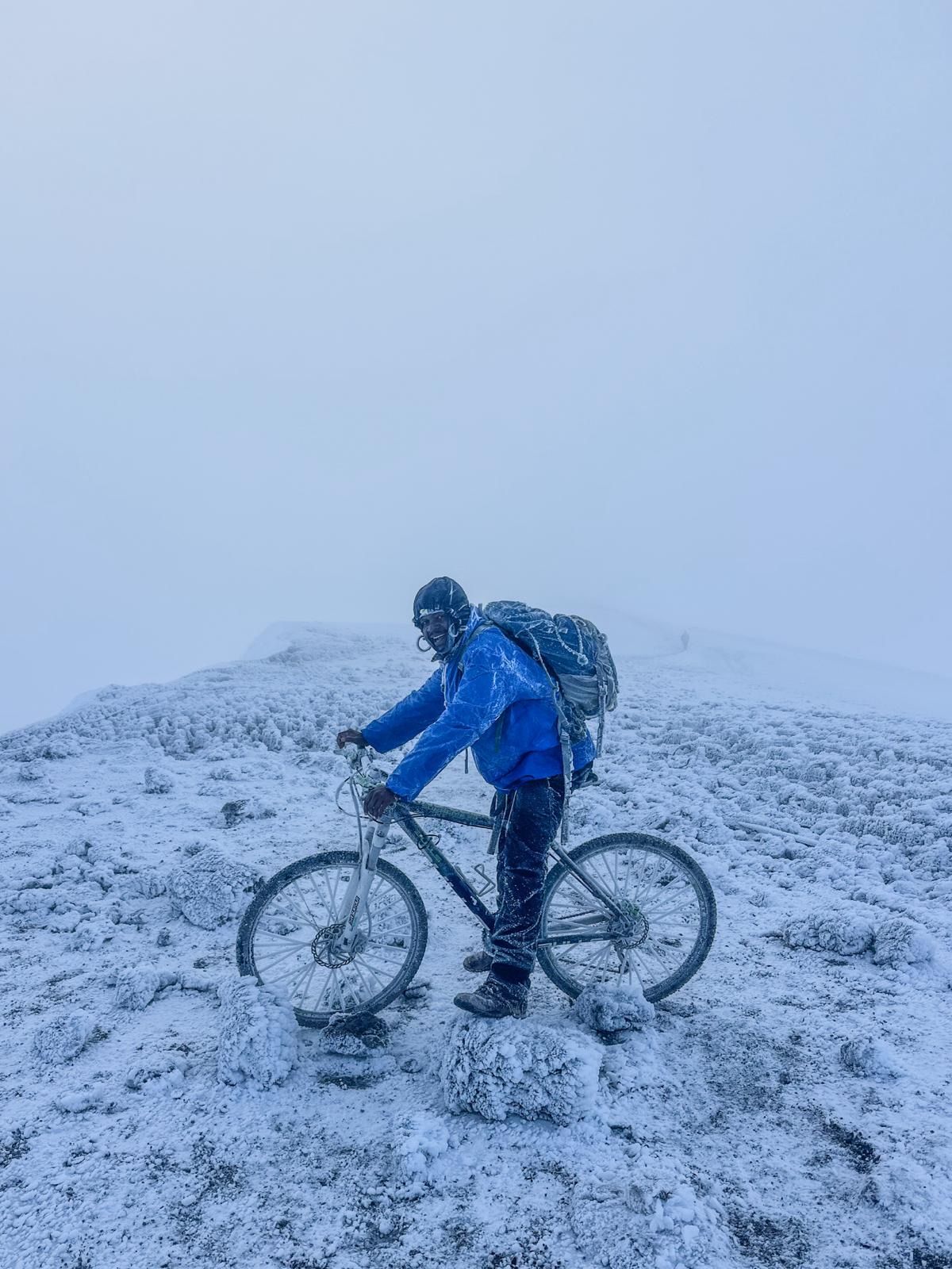 A crew member with a bicycle on the snowy crater rim